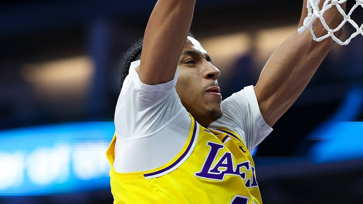 Cameron Carr hangs from the rim in a gold Lakers jersey after a dunk.