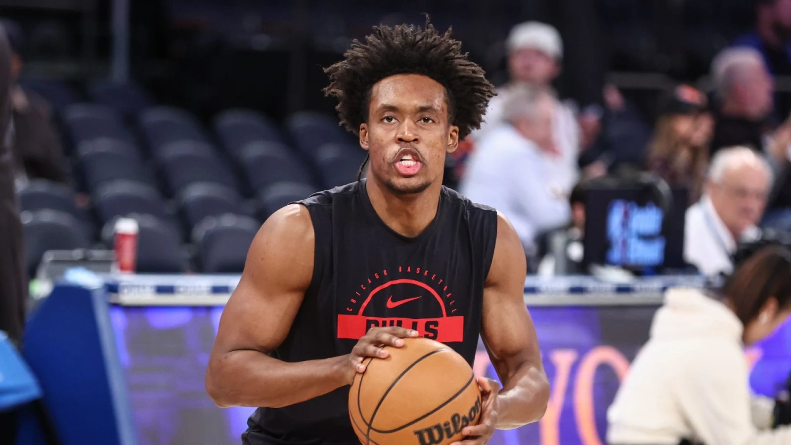 Collin Sexton holds a basketball while wearing a black Chicago Bulls warmup shirt.