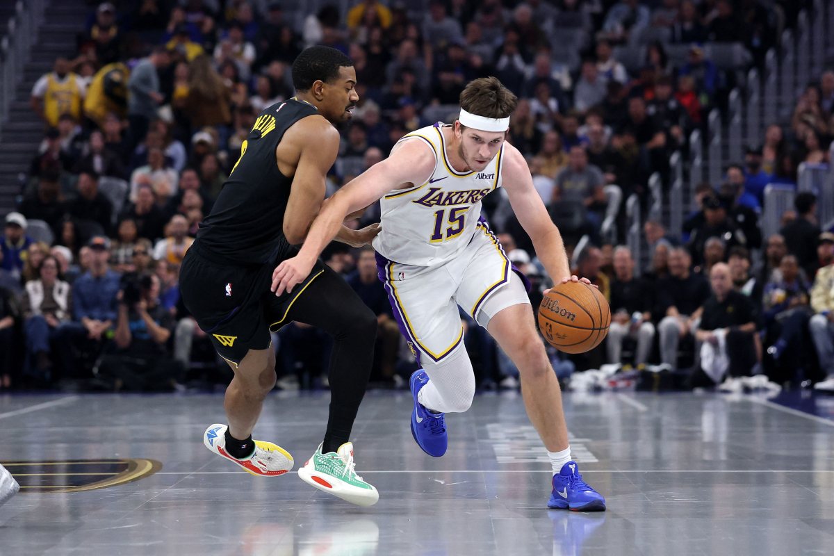 Austin Reaves, in a white Lakers No. 15 jersey and headband, drives with his left hand past De'Anthony Melton of the Warriors in a black jersey.