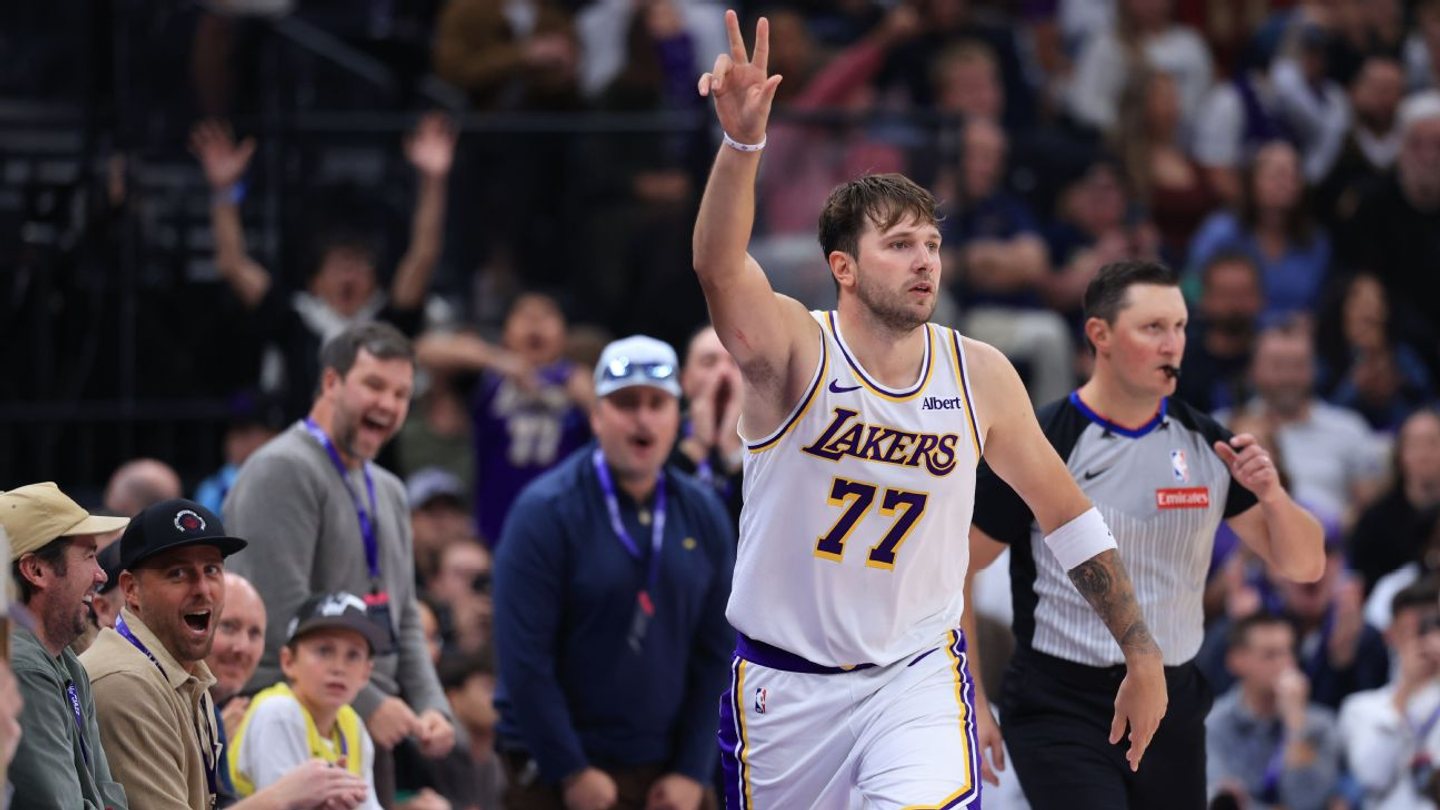 Luka Doncic raises his hand in a white No. 77 Lakers uniform.