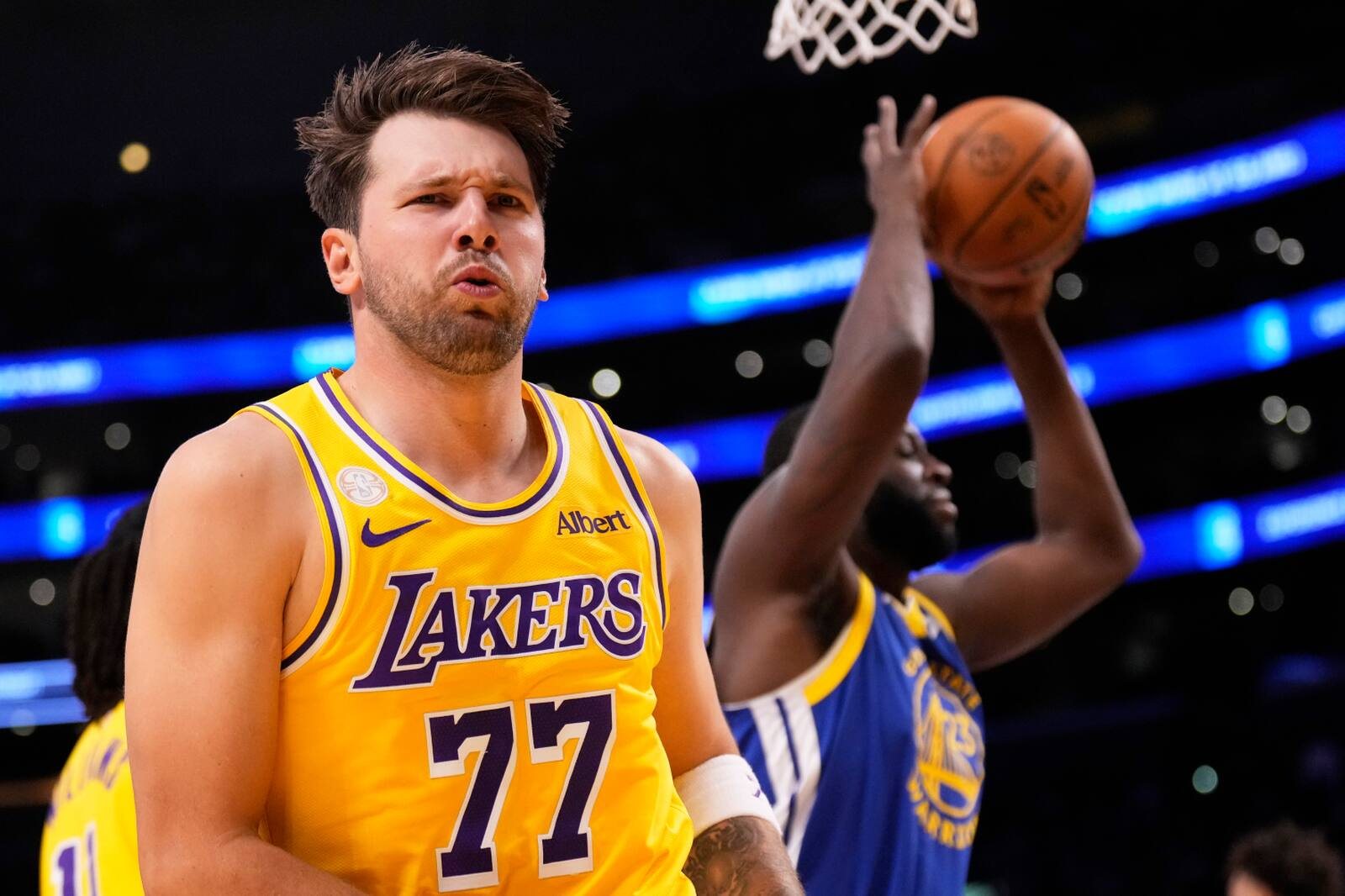 Luka Doncic in a gold Lakers jersey with Draymond Green behind him.