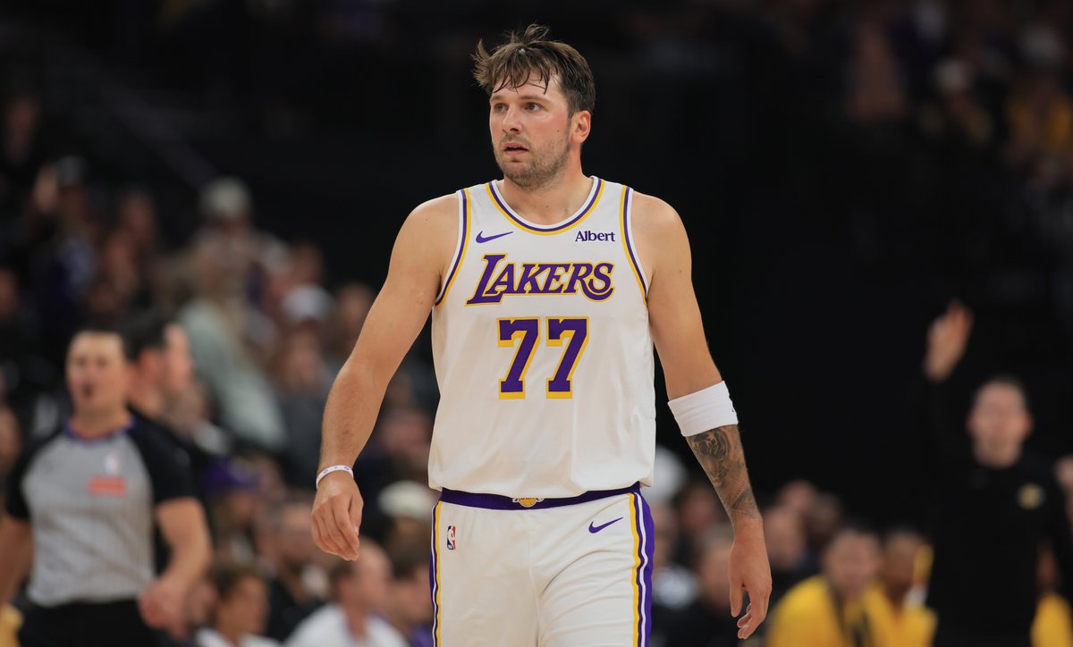 Luka Doncic walks up the court in a white Lakers jersey during the first half in Salt Lake City.