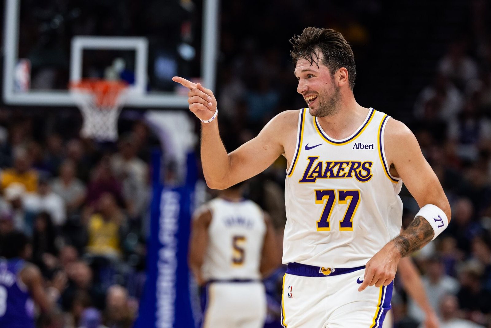 Luka Doncic in a white Lakers No. 77 jersey points and smiles during a game.