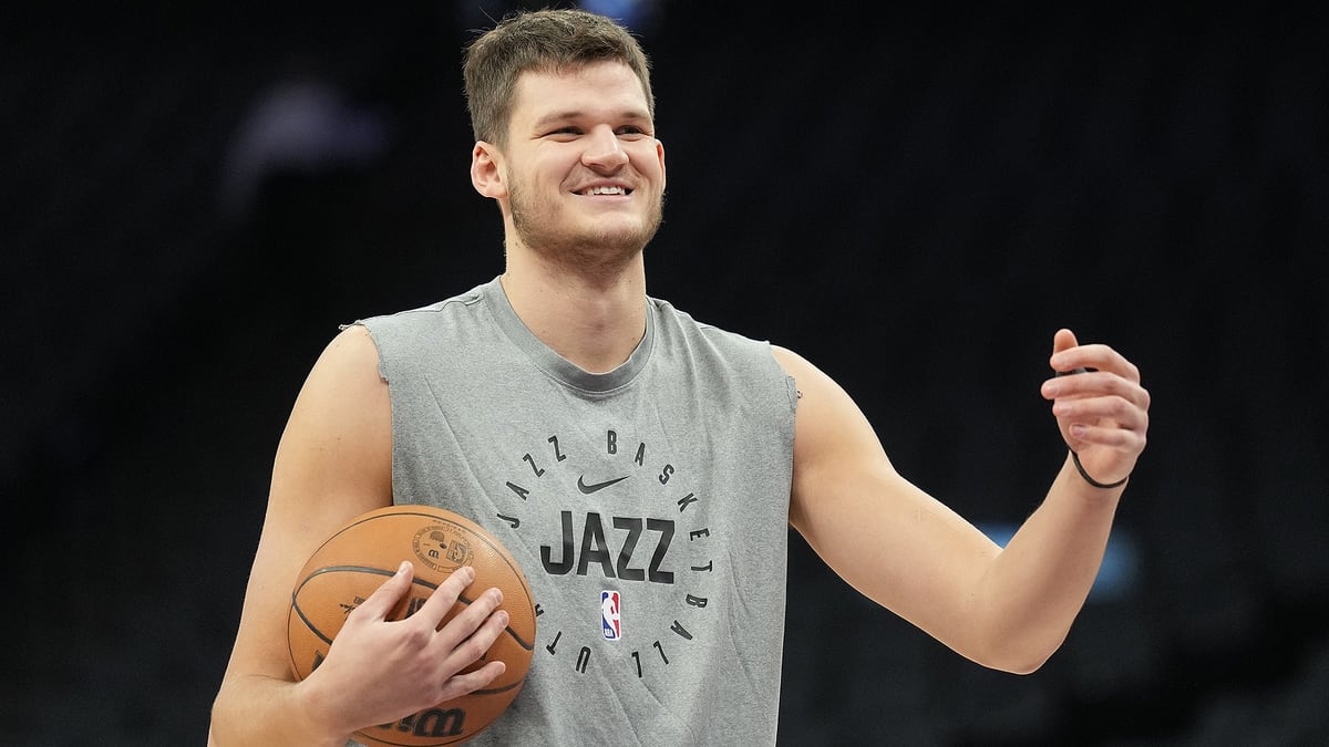 Walker Kessler smiles and holds a basketball during Utah Jazz warmups.