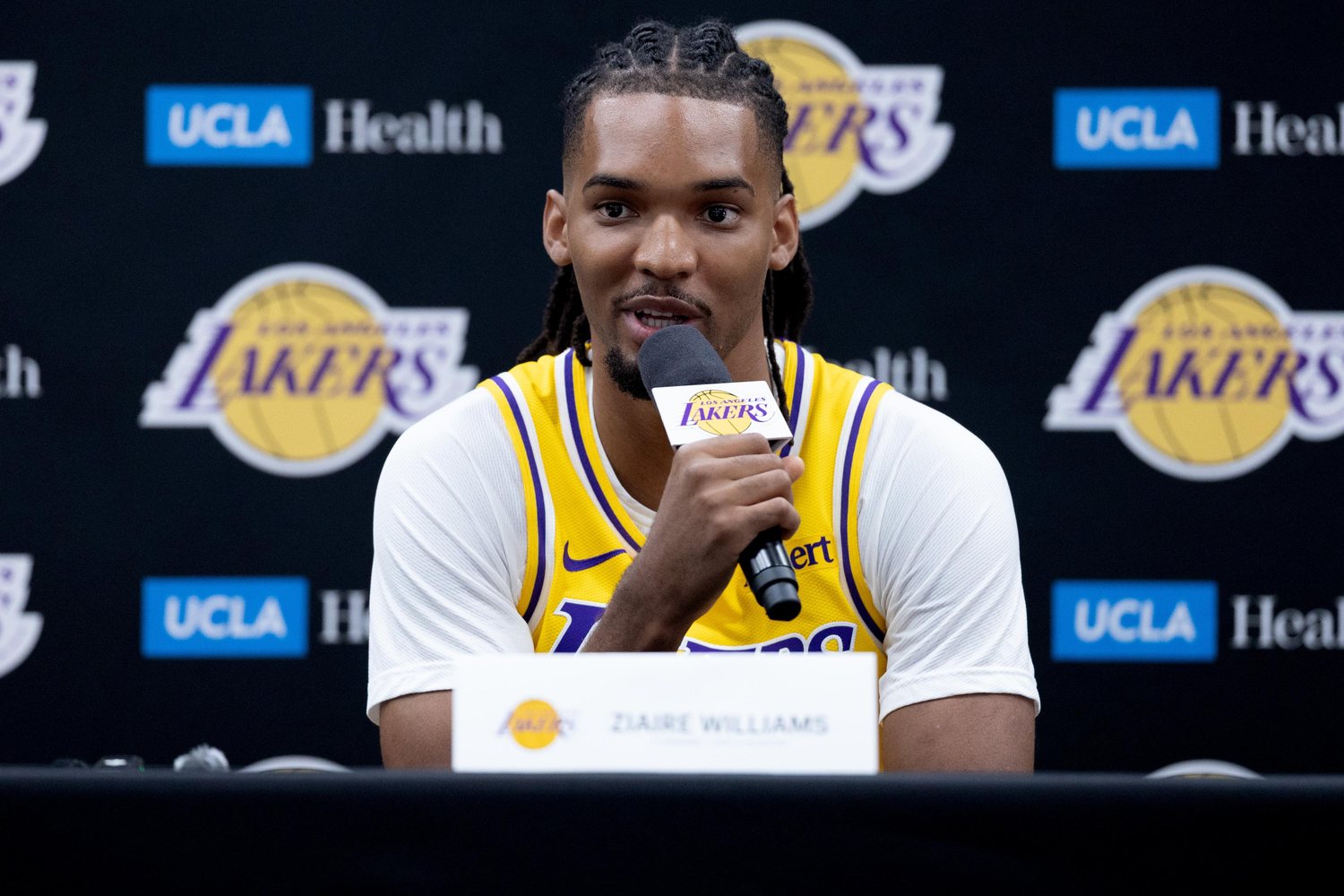 Ziaire Williams holds a microphone while wearing a gold Lakers jersey at media day.